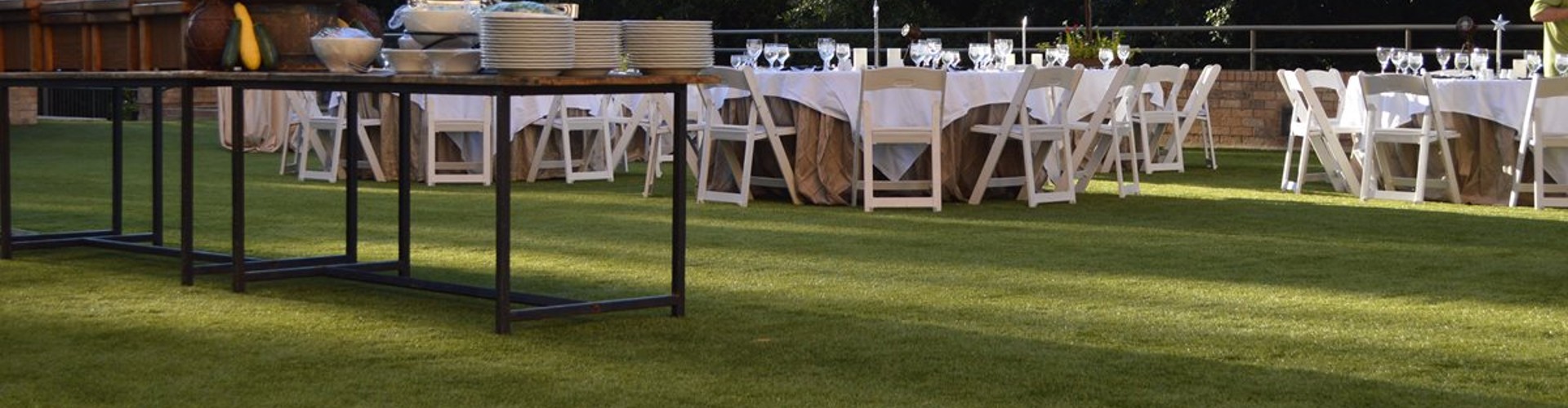 Artificial turf lawn at a resort event space set for an outdoor catered dinner reception